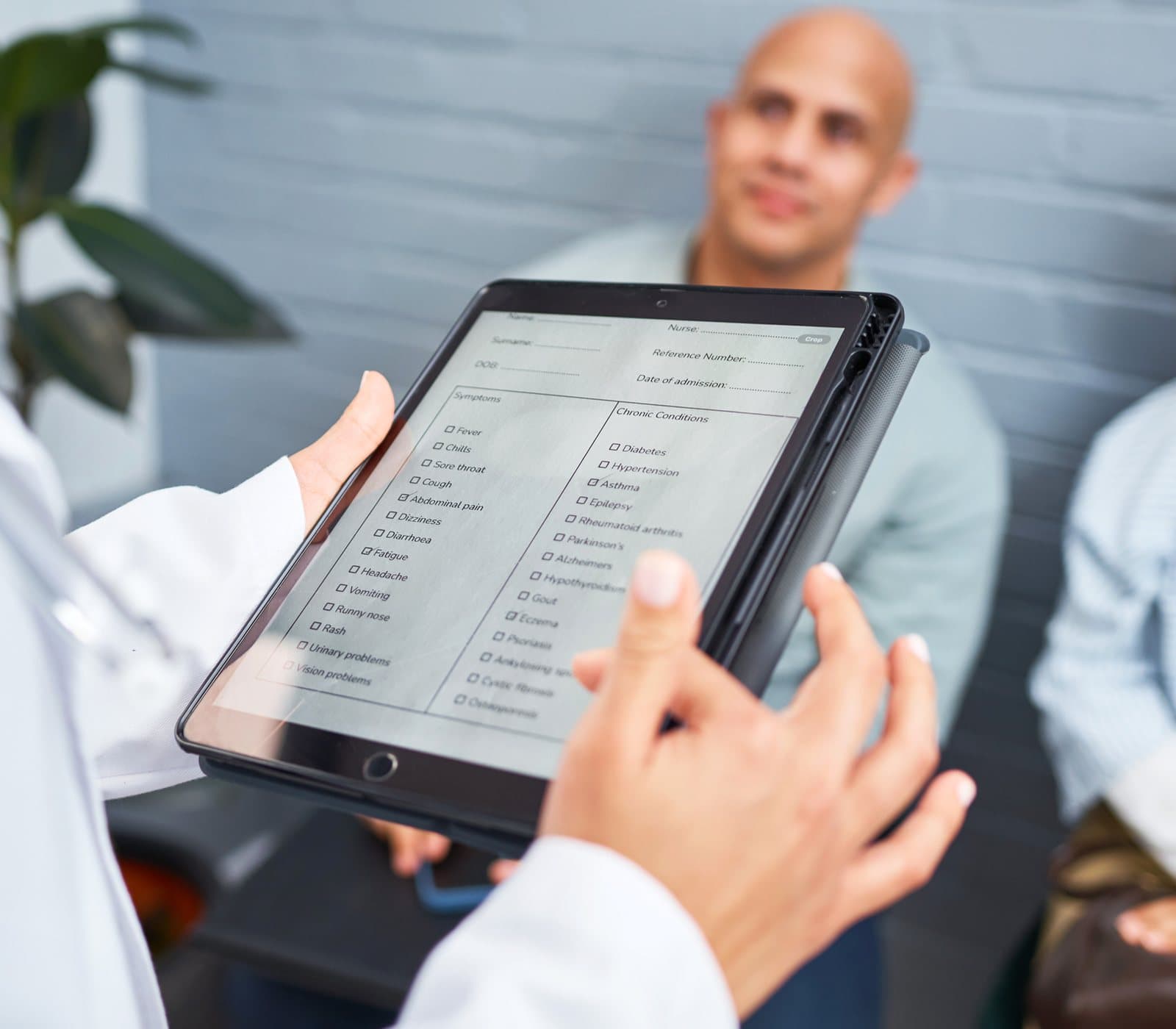 A clinician showing a patient a form on a tablet in a waiting room